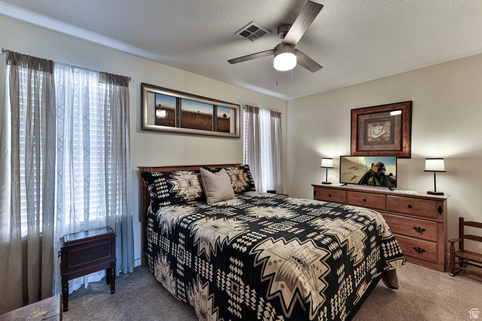 Bedroom with a ceiling fan, visible vents, carpet floors, and a textured ceiling