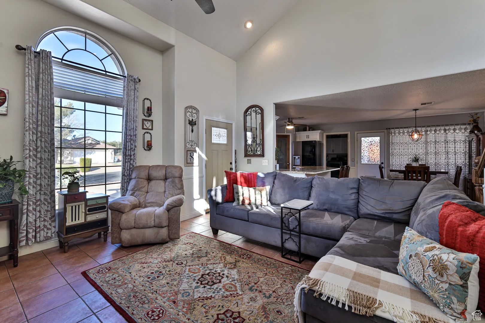 Living area with tile patterned floors, high vaulted ceiling, and ceiling fan