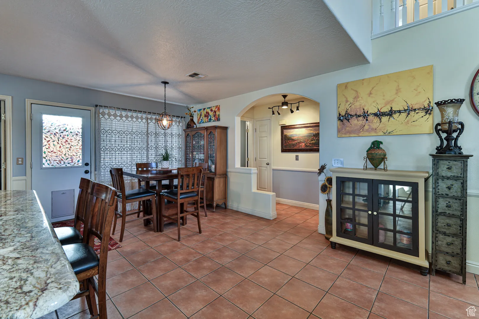 Dining space with tile patterned flooring, visible vents, baseboards, arched walkways, and a textured ceiling