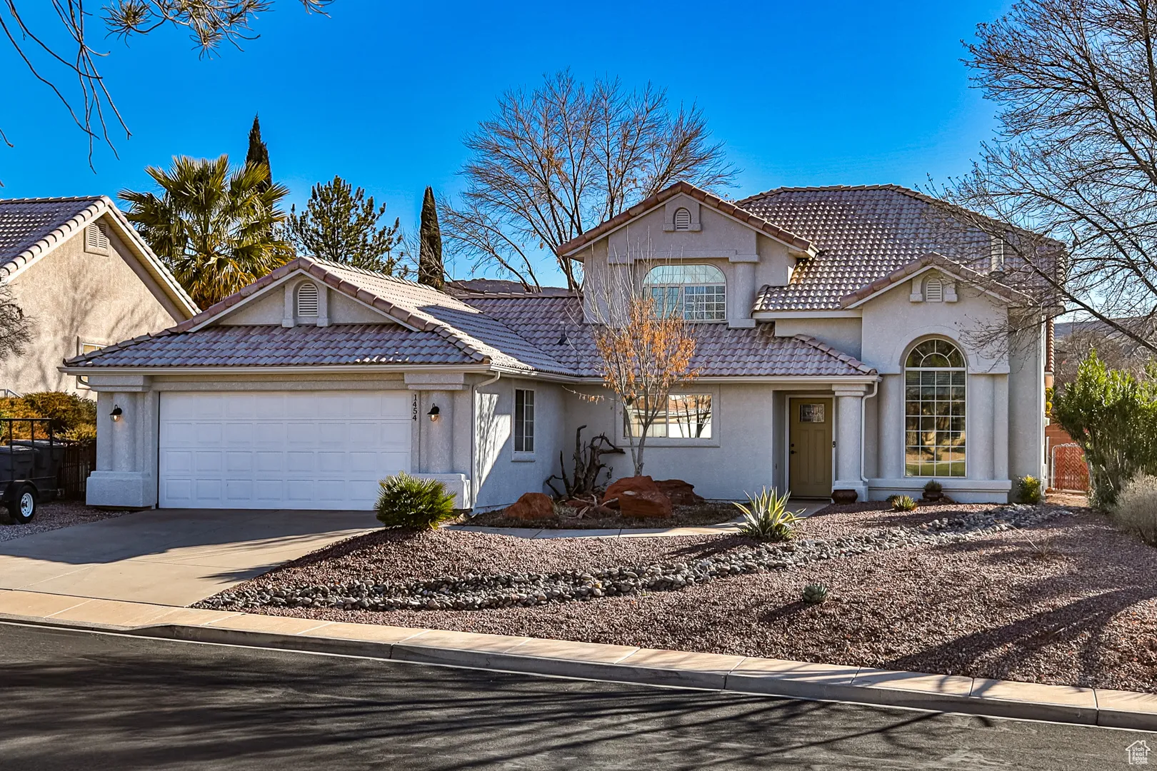 View of front of house featuring stucco siding, a tiled roof, concrete driveway, and an attached garage