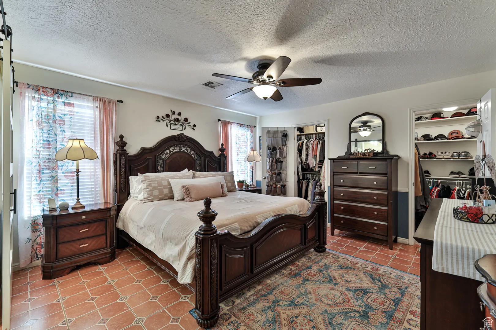 Bedroom featuring light tile patterned floors, visible vents, a textured ceiling, and ceiling fan