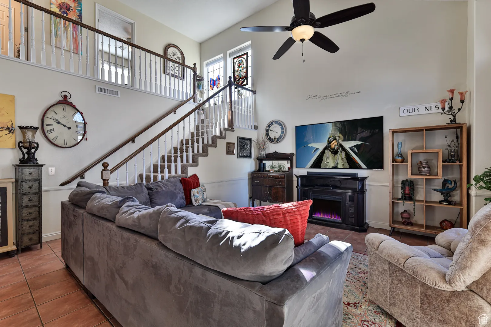 Living area with visible vents, stairs, a towering ceiling, tile patterned floors, and a glass covered fireplace