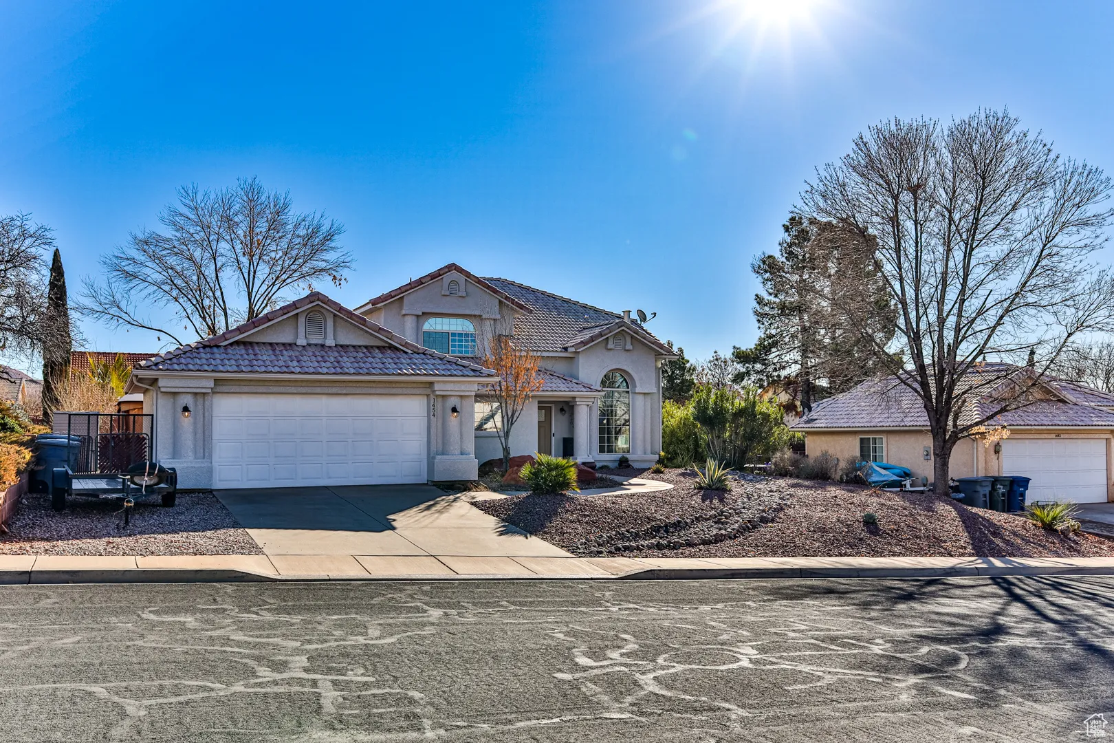 View of front of home featuring a garage, driveway, stucco siding, and a tile roof