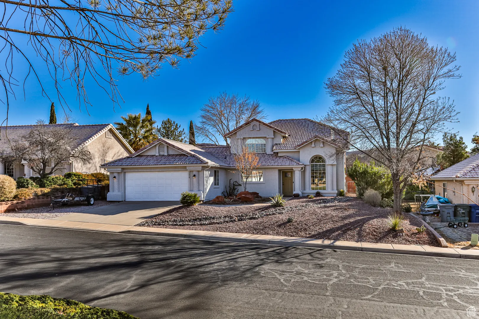 View of front of property featuring a tile roof, stucco siding, concrete driveway, and a garage