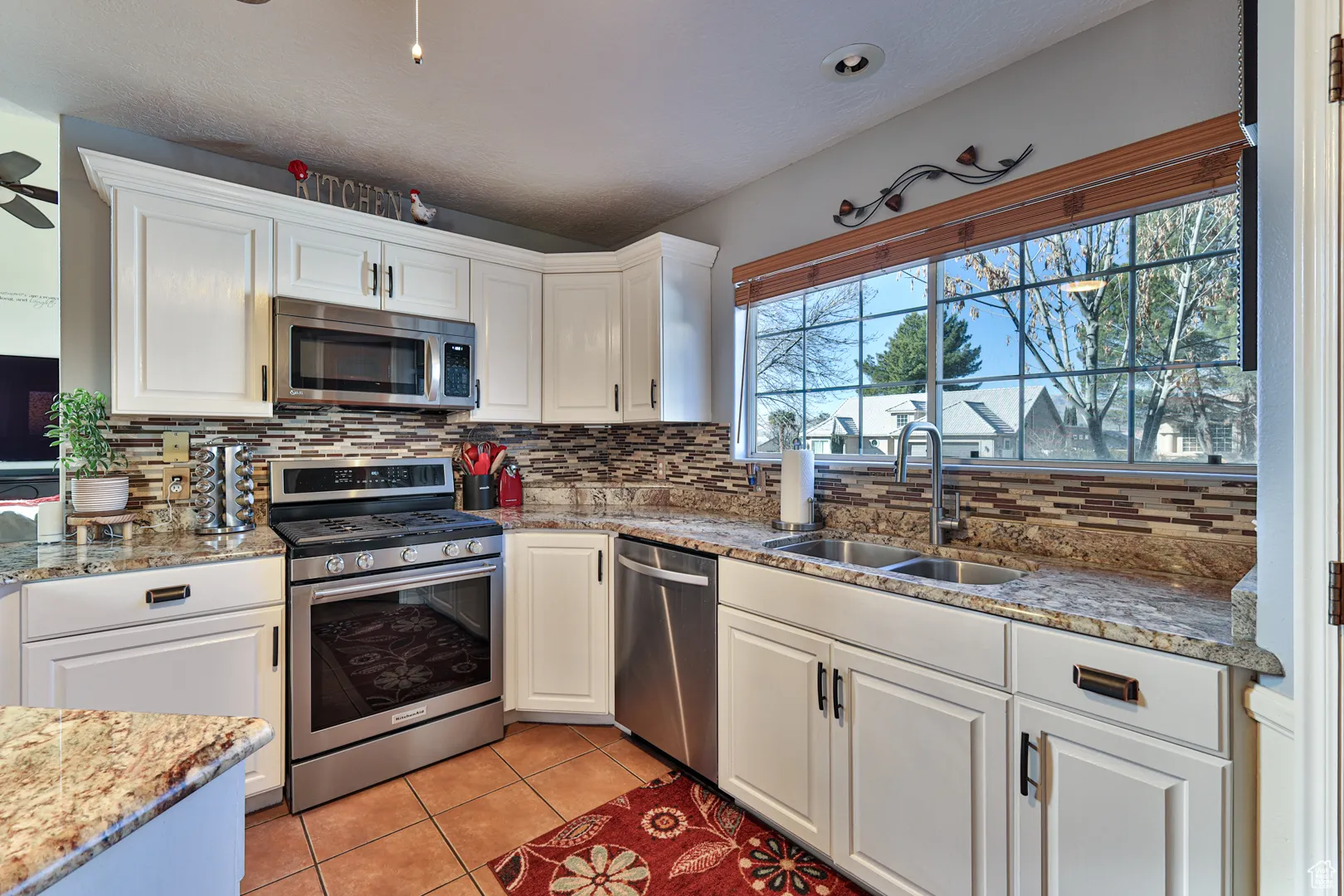 Kitchen featuring light tile patterned floors, white cabinets, stainless steel appliances, and a sink
