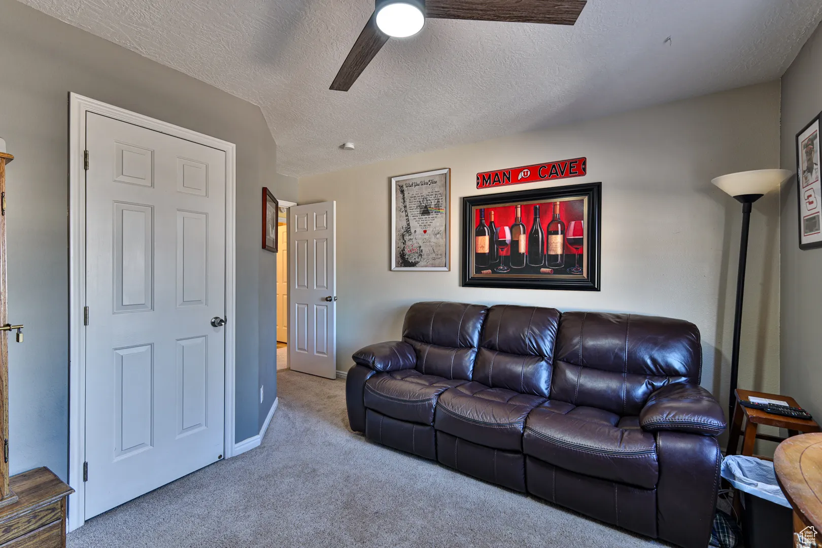 Living area featuring a textured ceiling, baseboards, a ceiling fan, and carpet floors