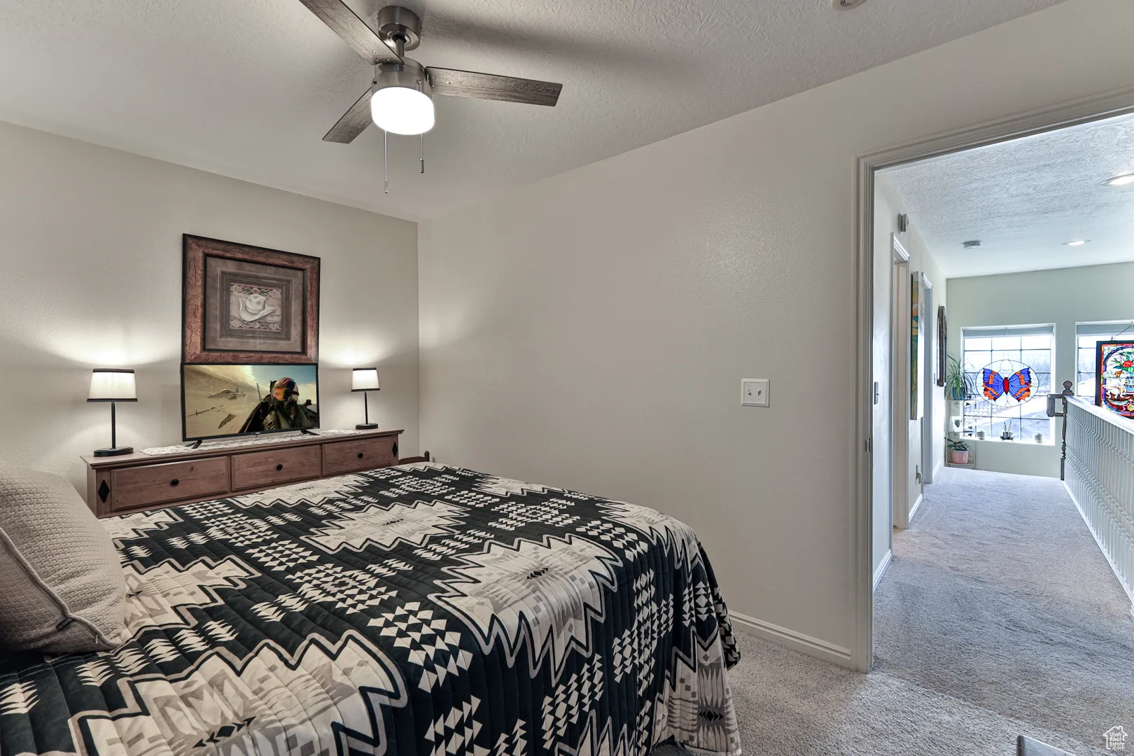 Bedroom featuring a ceiling fan, light colored carpet, baseboards, and a textured ceiling