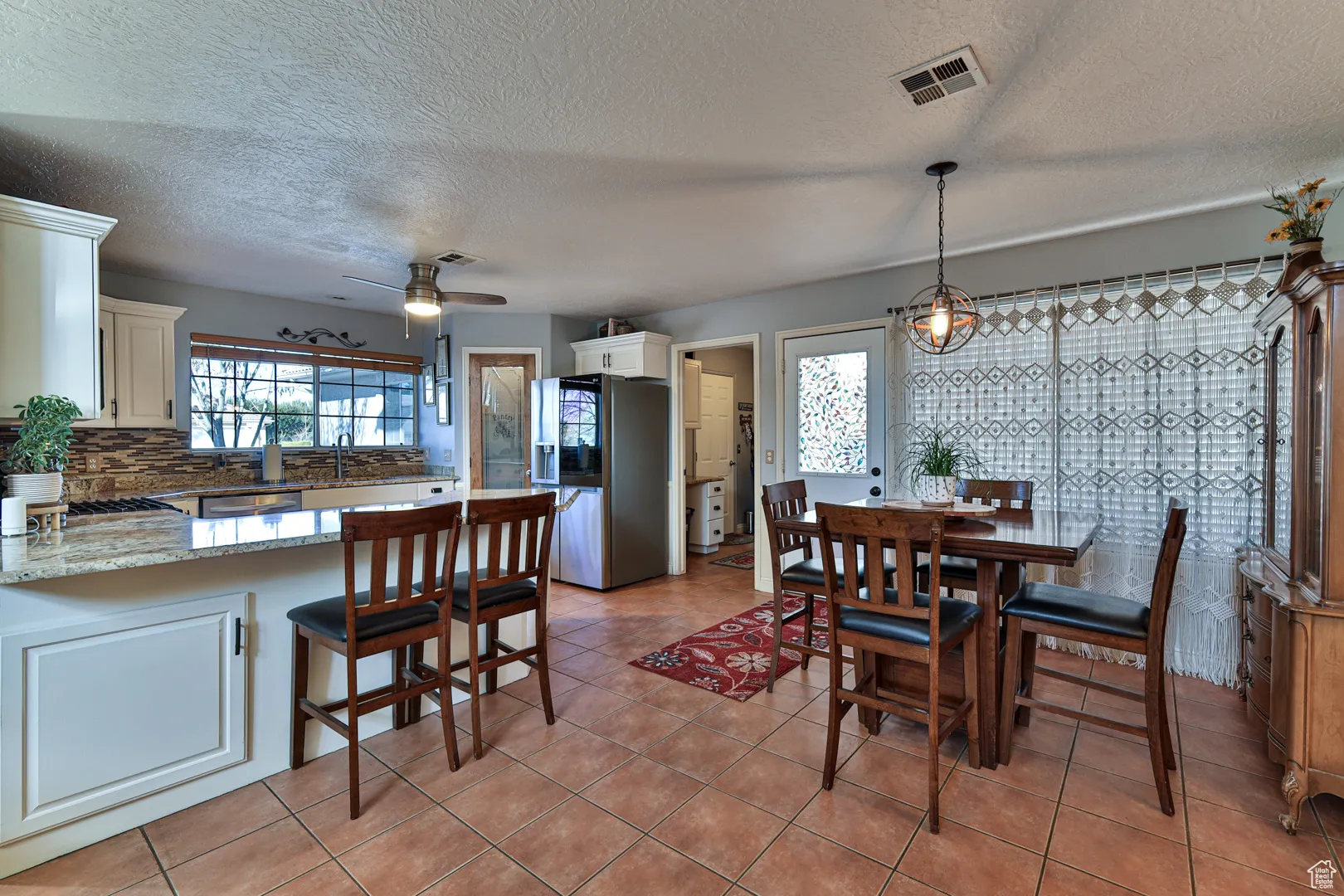 Dining space featuring light tile patterned floors, visible vents, a textured ceiling, and ceiling fan