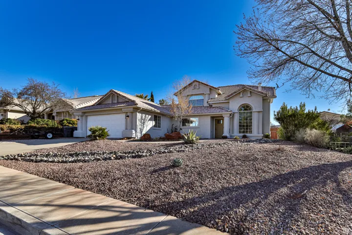 View of front of house with a tiled roof, a garage, driveway, and stucco siding