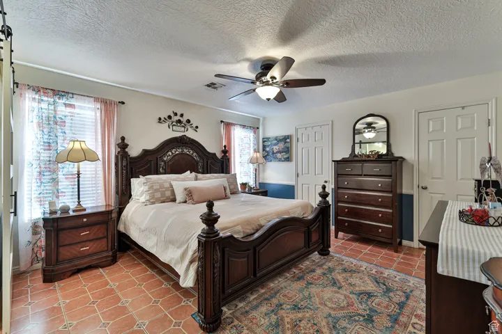 Bedroom with light tile patterned flooring, visible vents, a textured ceiling, and ceiling fan