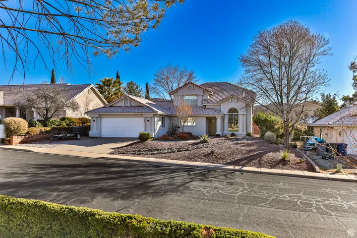 View of front of house featuring a tiled roof, stucco siding, driveway, and an attached garage