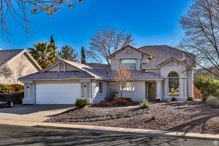 View of front of house with stucco siding, concrete driveway, an attached garage, and a tiled roof