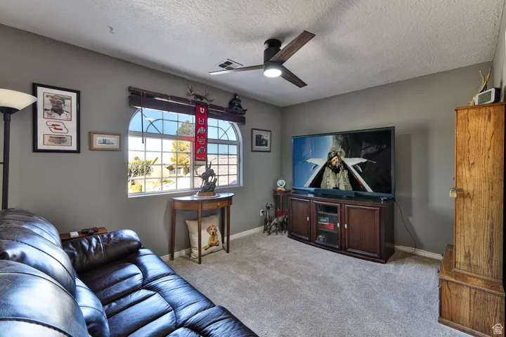Living area with visible vents, baseboards, carpet, and ceiling fan