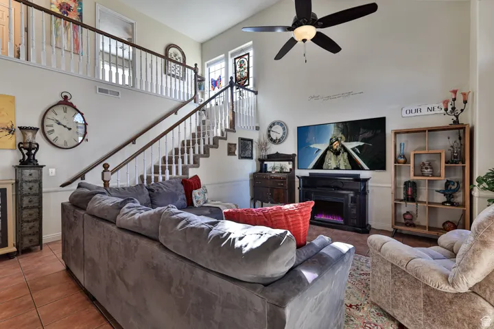 Living area with visible vents, stairs, a towering ceiling, tile patterned floors, and a glass covered fireplace