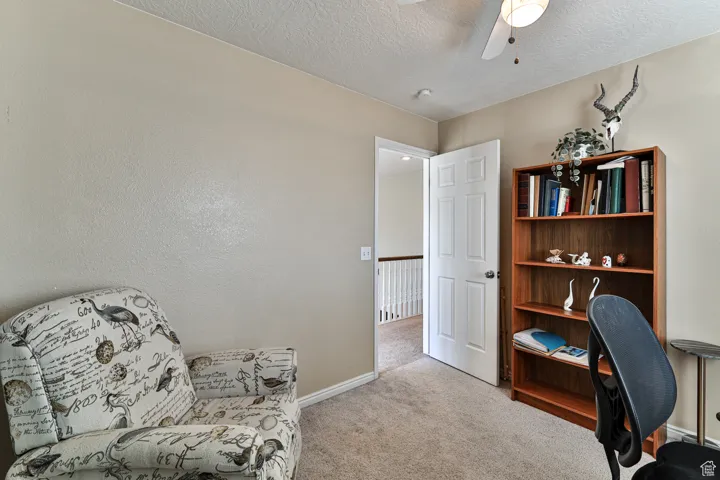 Carpeted office featuring baseboards, a textured ceiling, and a ceiling fan