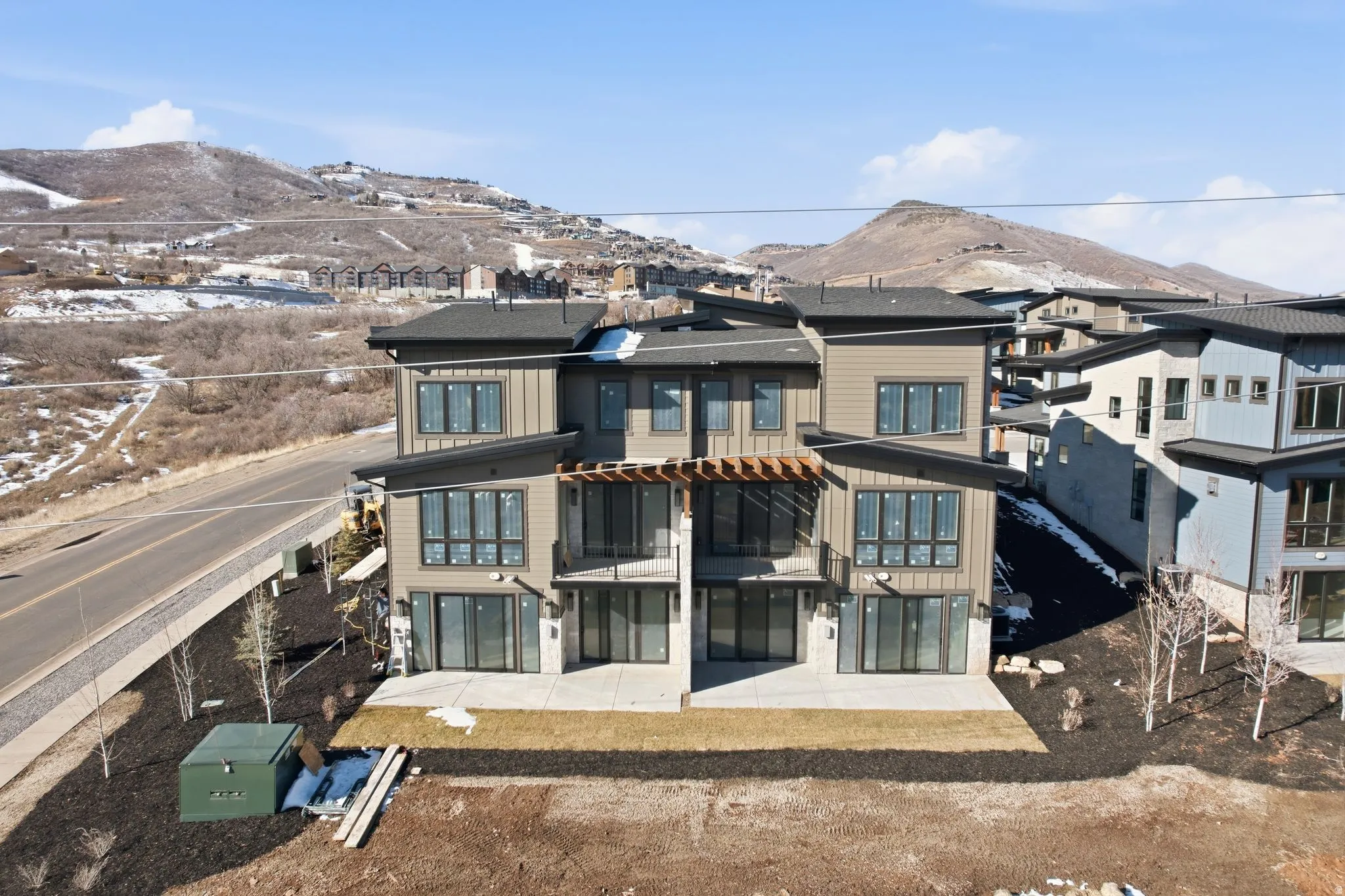 View of front facade with a patio, a mountain view, roof with shingles, and board and batten siding