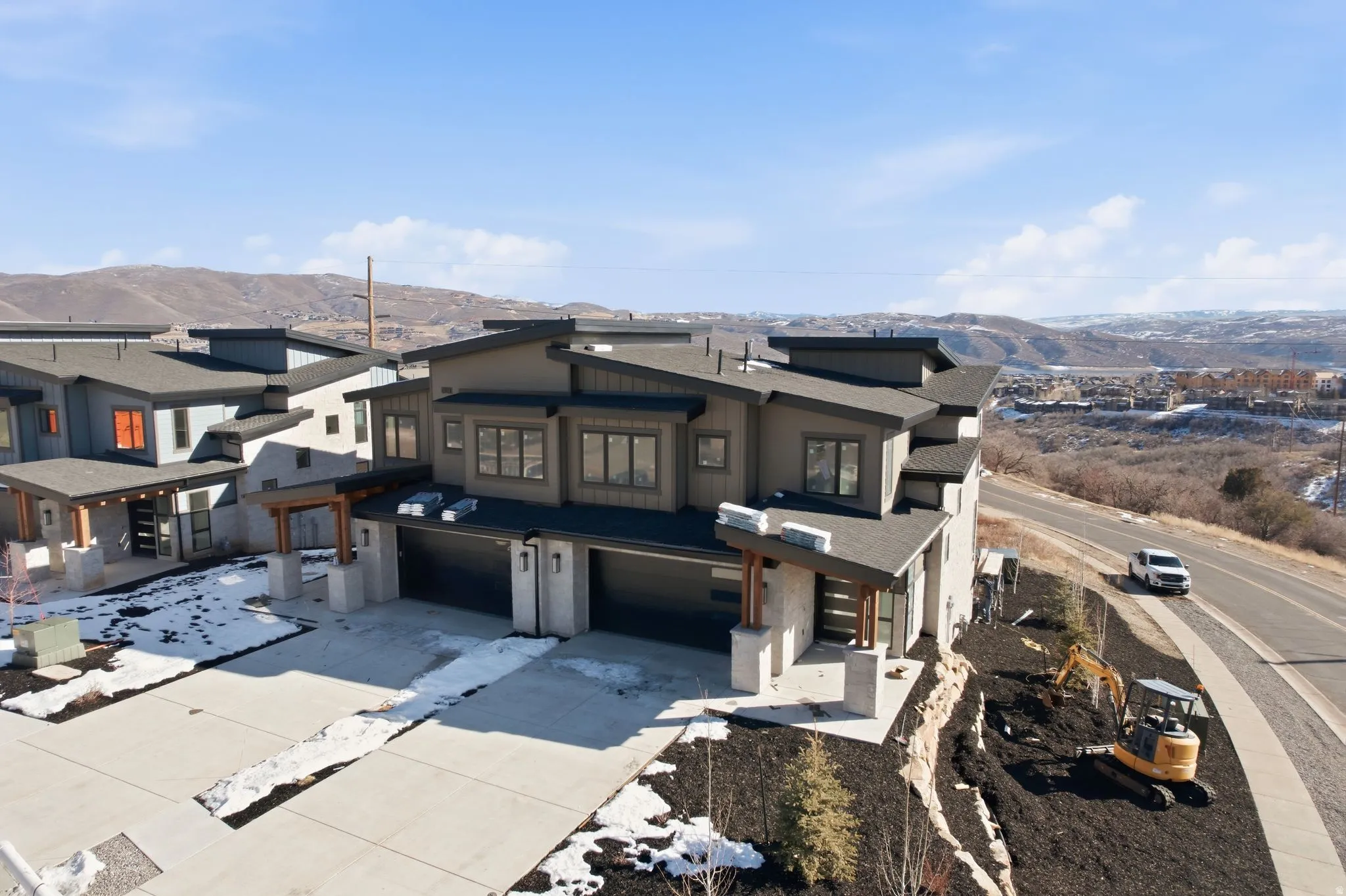 View of front of property with a mountain view, a garage, driveway, and a residential view