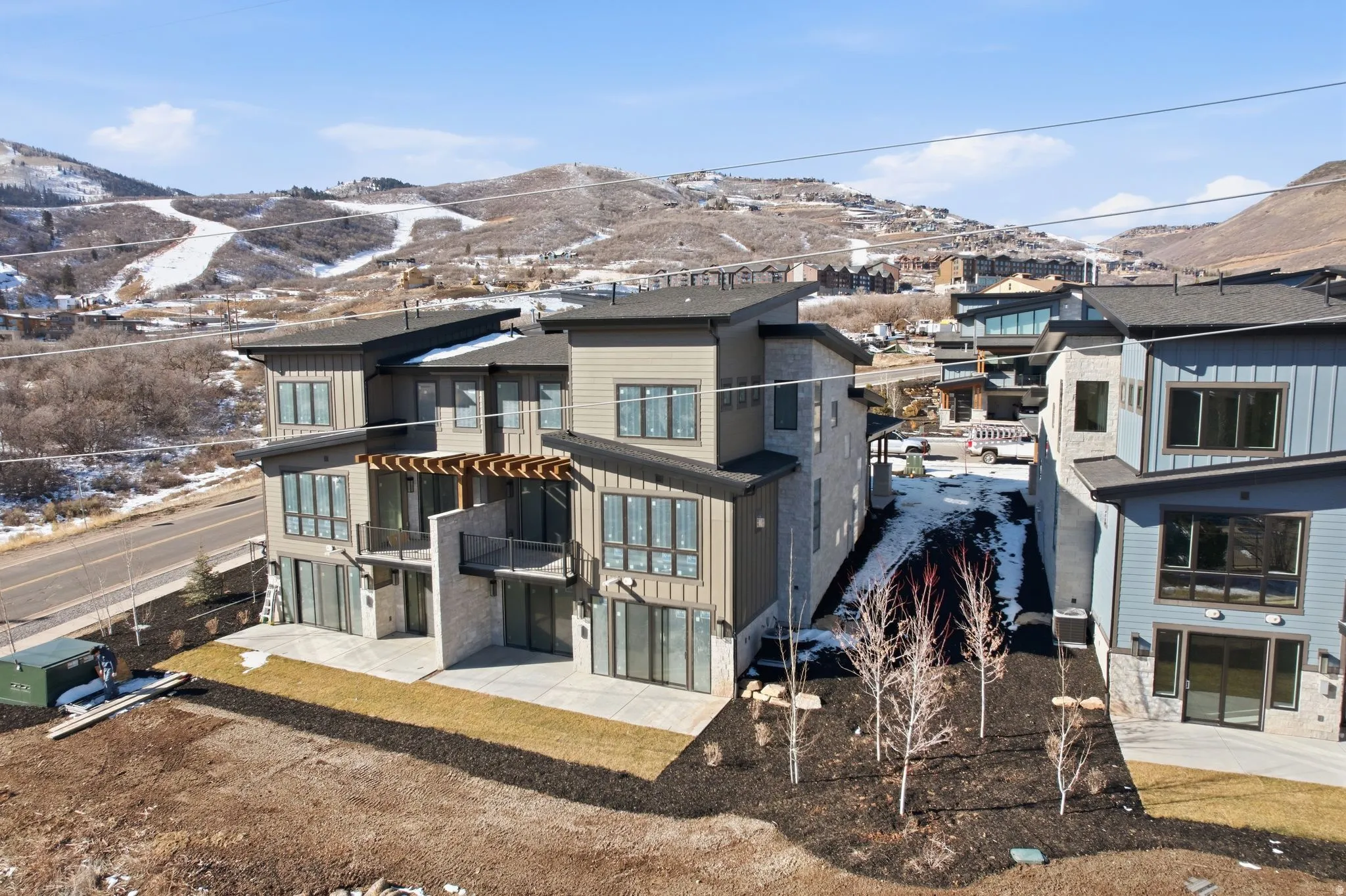 Rear view of property featuring a mountain view, a patio area, board and batten siding, a balcony, and a pergola