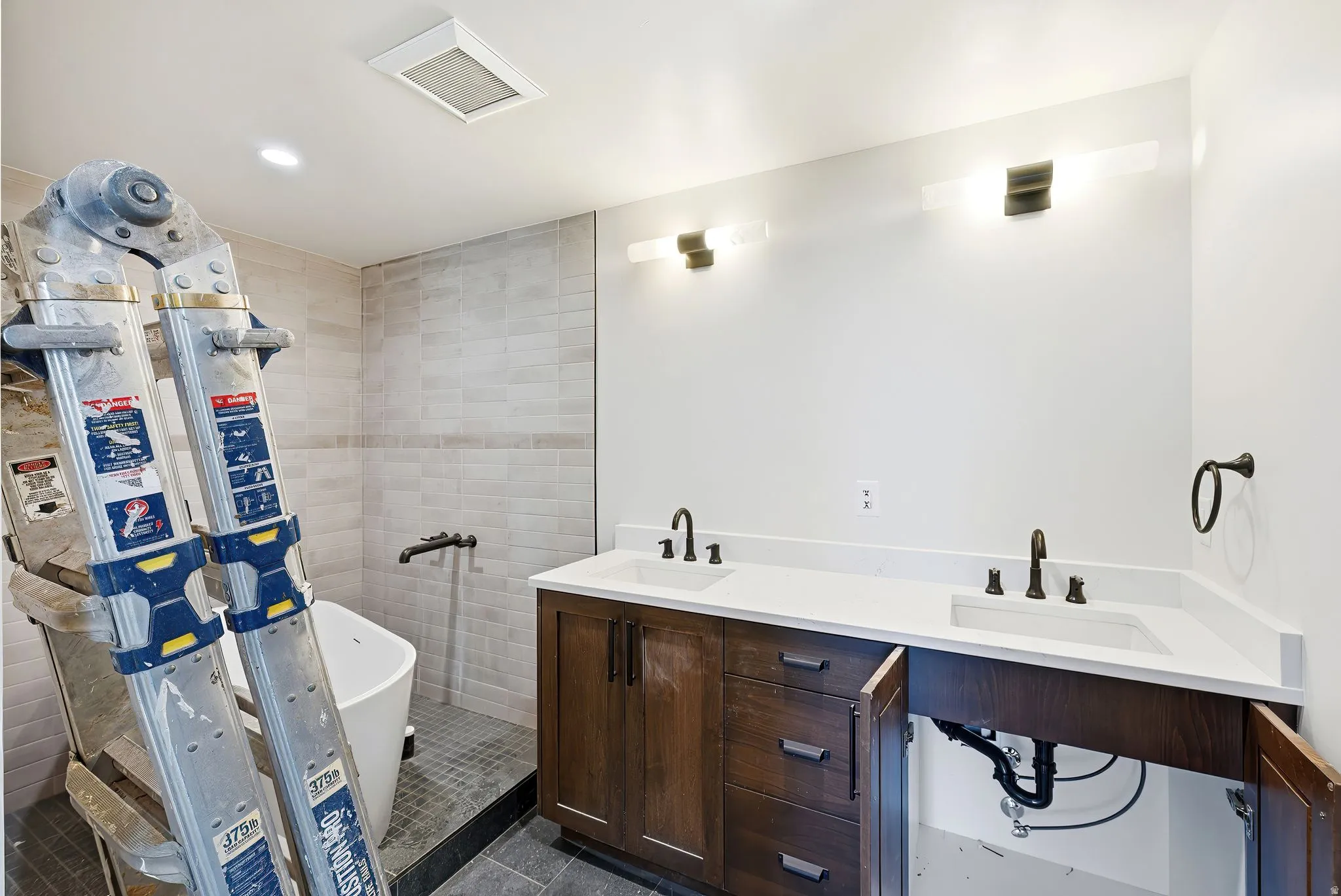 Bathroom featuring double vanity, a soaking tub, dark tile patterned flooring, recessed lighting, and a stall shower