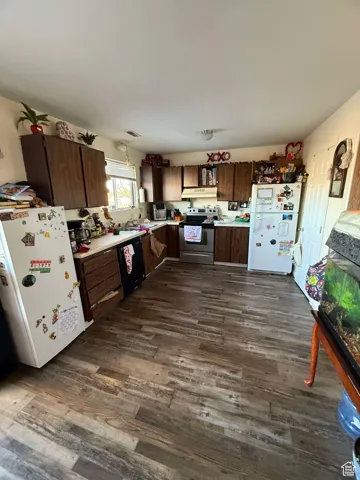 Kitchen with freestanding refrigerator, dark wood-style floors, electric stove, and black dishwasher