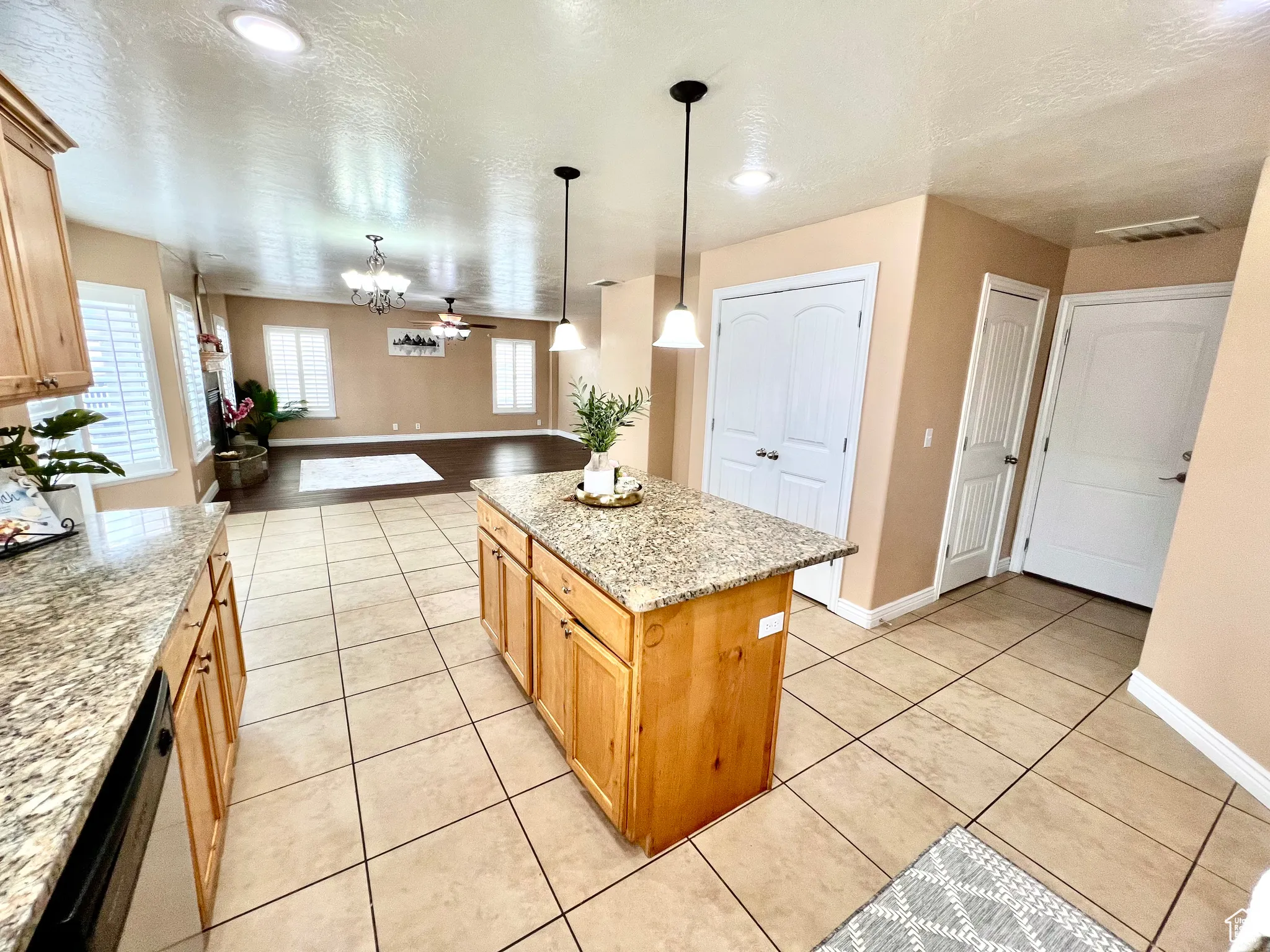 Kitchen with light tile patterned flooring, visible vents, a center island, and light stone countertops