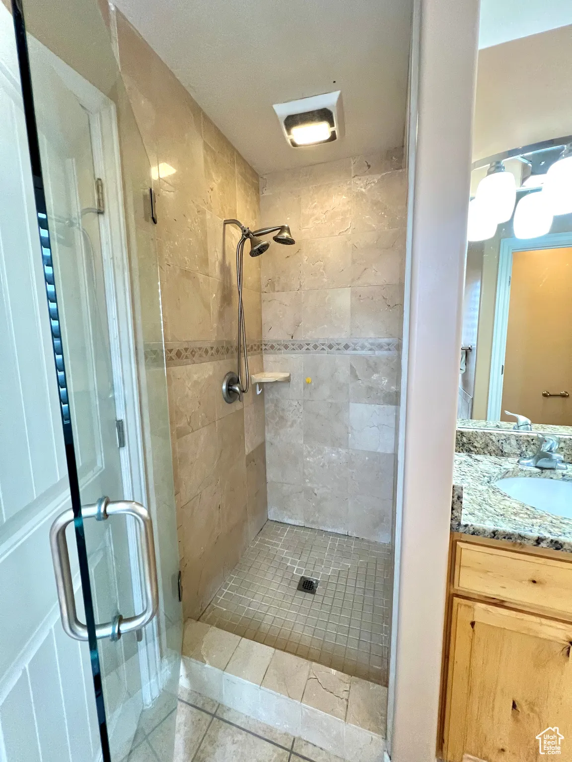 Bathroom with tile patterned floors, a shower stall, and vanity