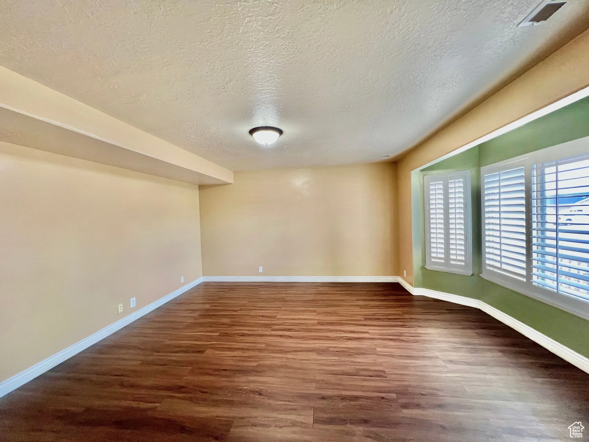 Spare room featuring wood finished floors, baseboards, and a textured ceiling