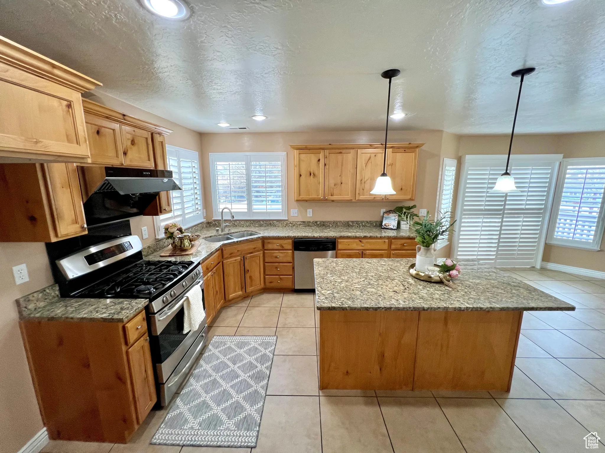 Kitchen with a sink, stainless steel appliances, plenty of natural light, and light tile patterned flooring