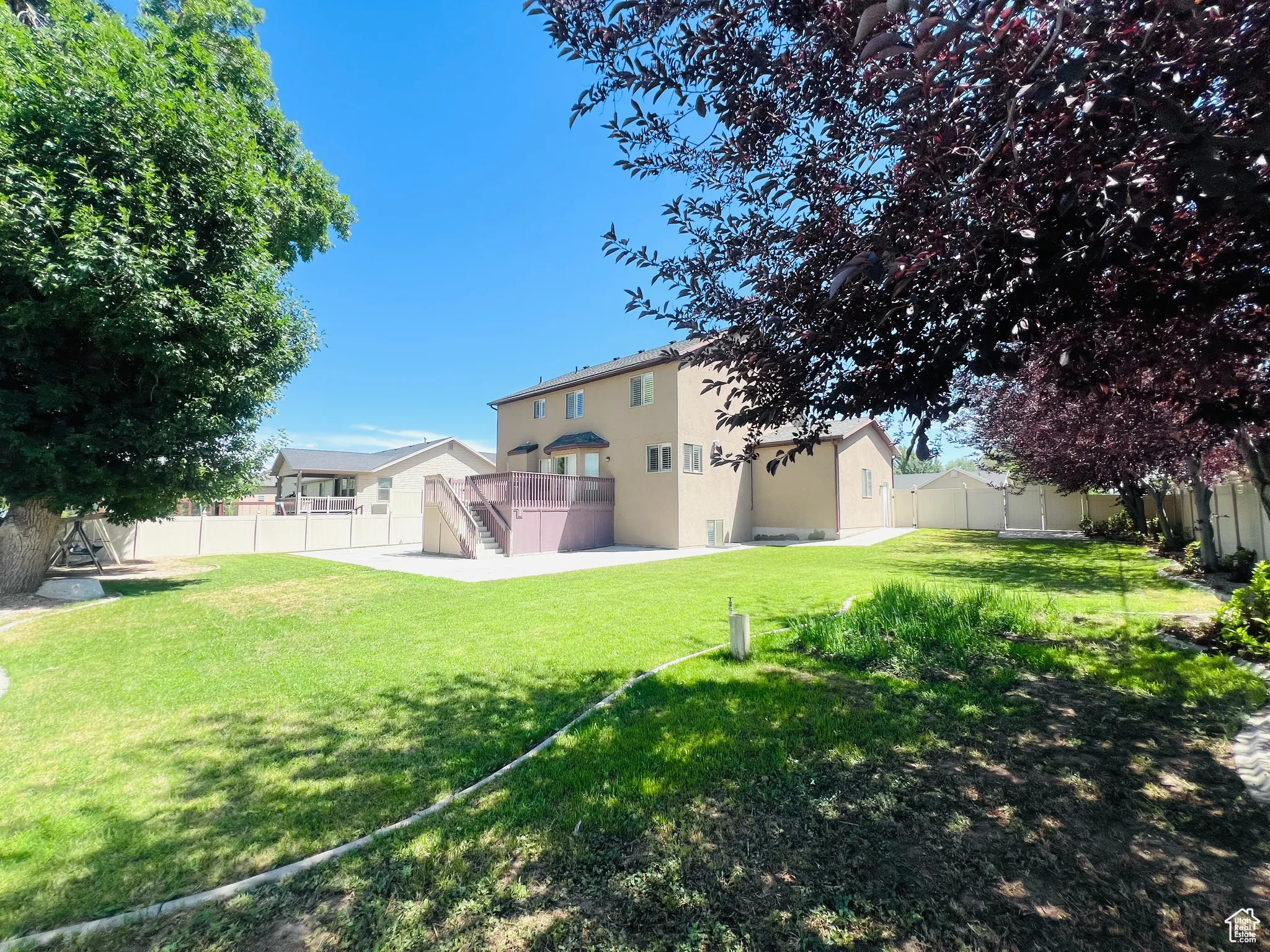 Back of property featuring a fenced backyard, stucco siding, stairs, and a wooden deck