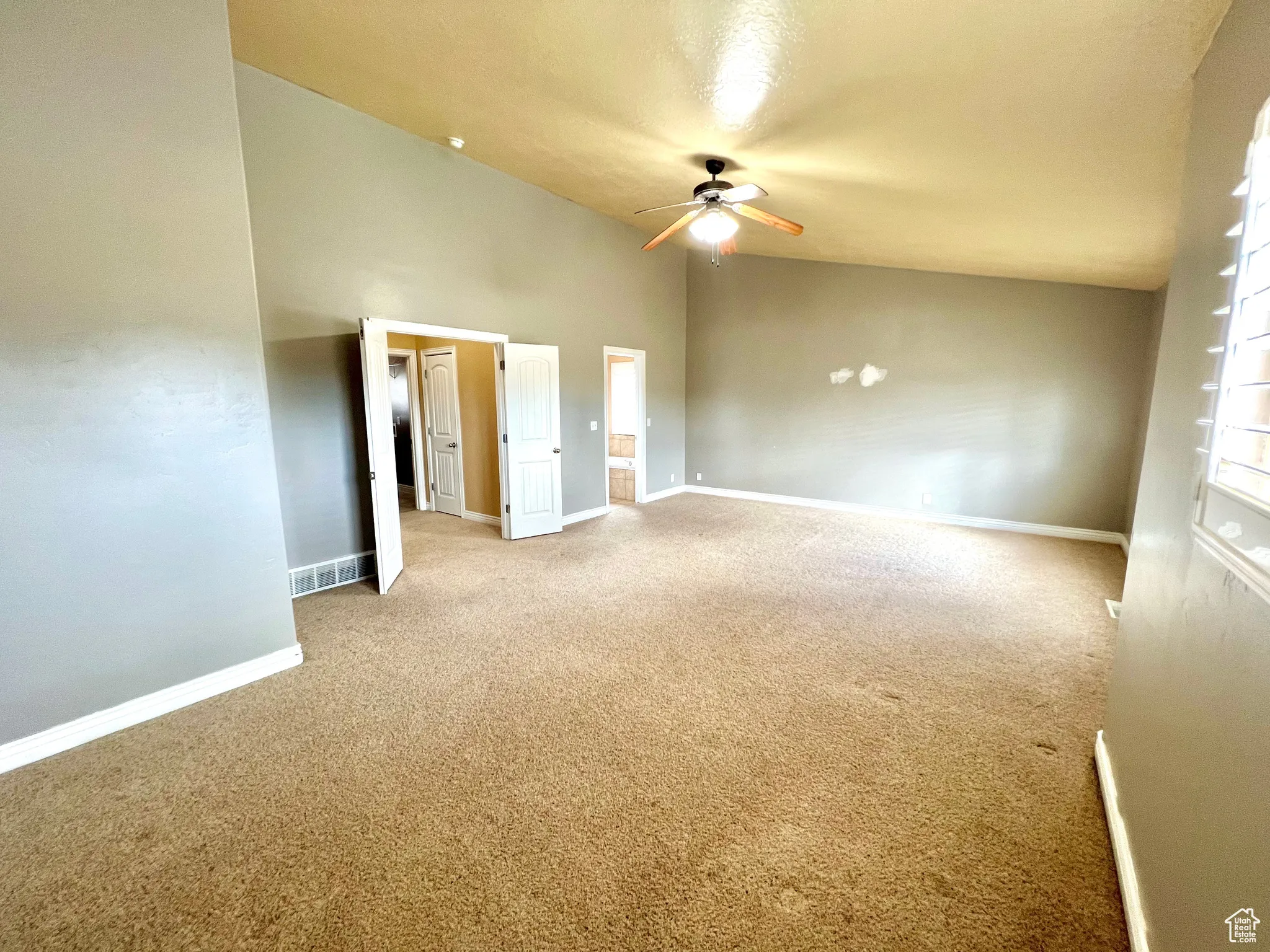 Interior space featuring lofted ceiling, baseboards, carpet floors, and ceiling fan