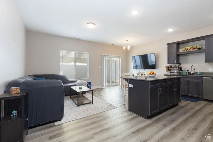 Kitchen featuring a kitchen island, a breakfast bar, LVP flooring, stainless steel dishwasher, and open floor plan