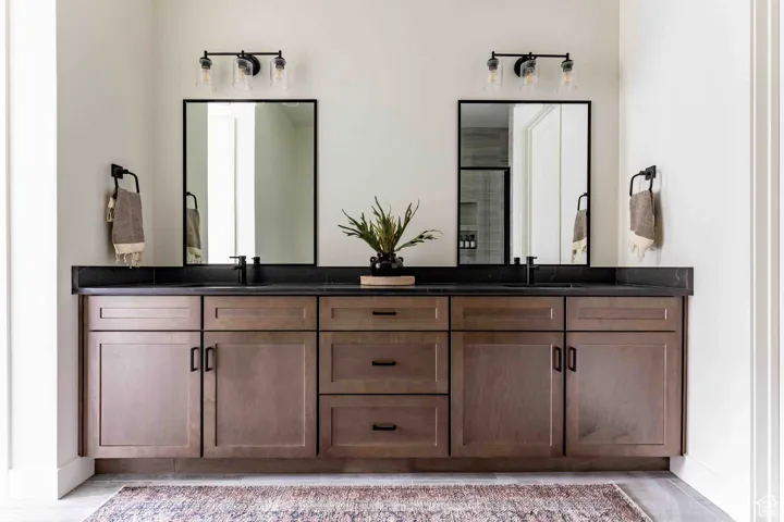 Bathroom featuring double vanity, a shower with door, and a sink