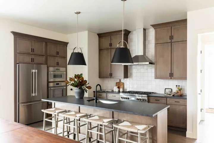 Kitchen with a sink, backsplash, dark countertops, appliances with stainless steel finishes, and wall chimney range hood