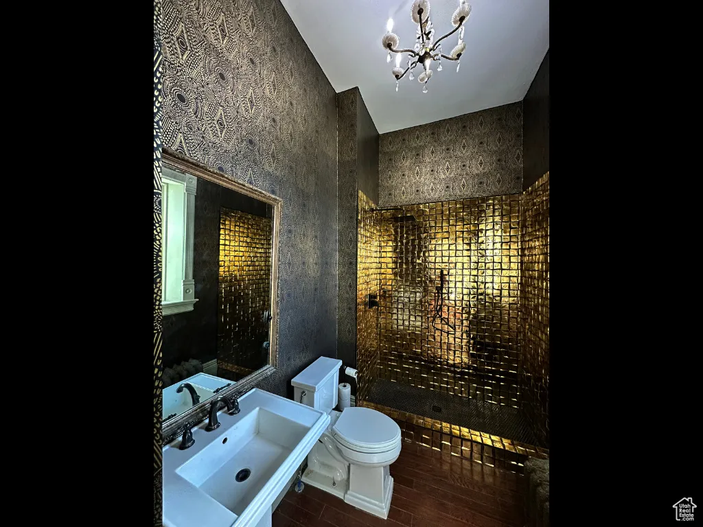 Bathroom featuring toilet, wood finished floors, a chandelier, and a sink