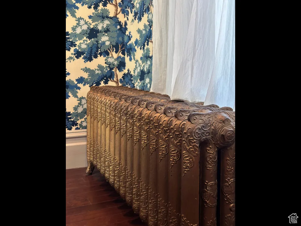 Bedroom with wallpapered walls and dark wood-type flooring