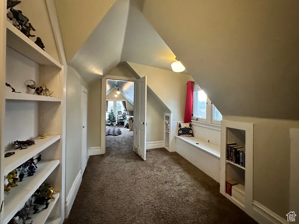 Bonus room featuring baseboards, lofted ceiling, and dark colored carpet