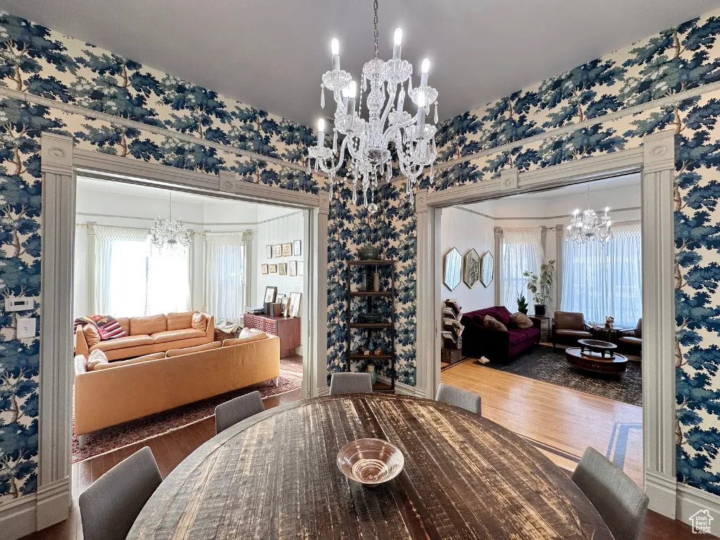 Dining area with a chandelier, wallpapered walls, and wood finished floors