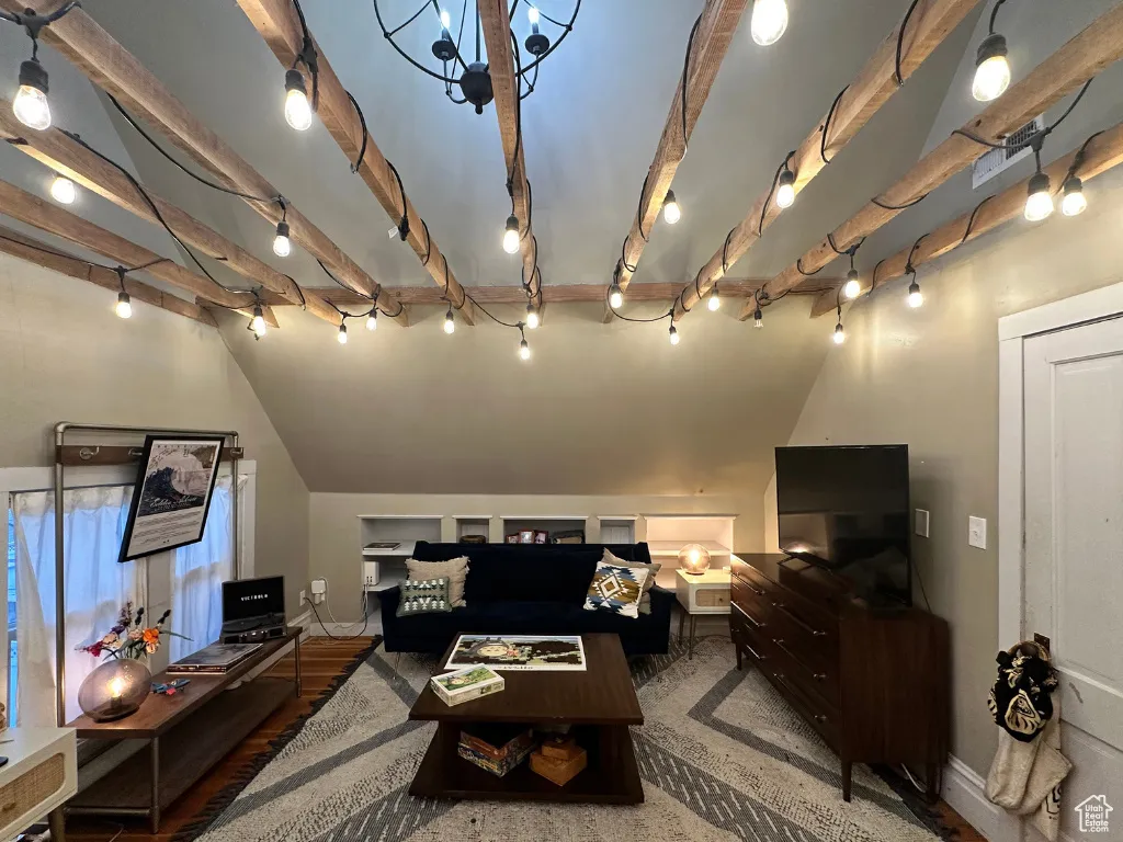 Living room featuring rail lighting, vaulted ceiling with beams, and baseboards