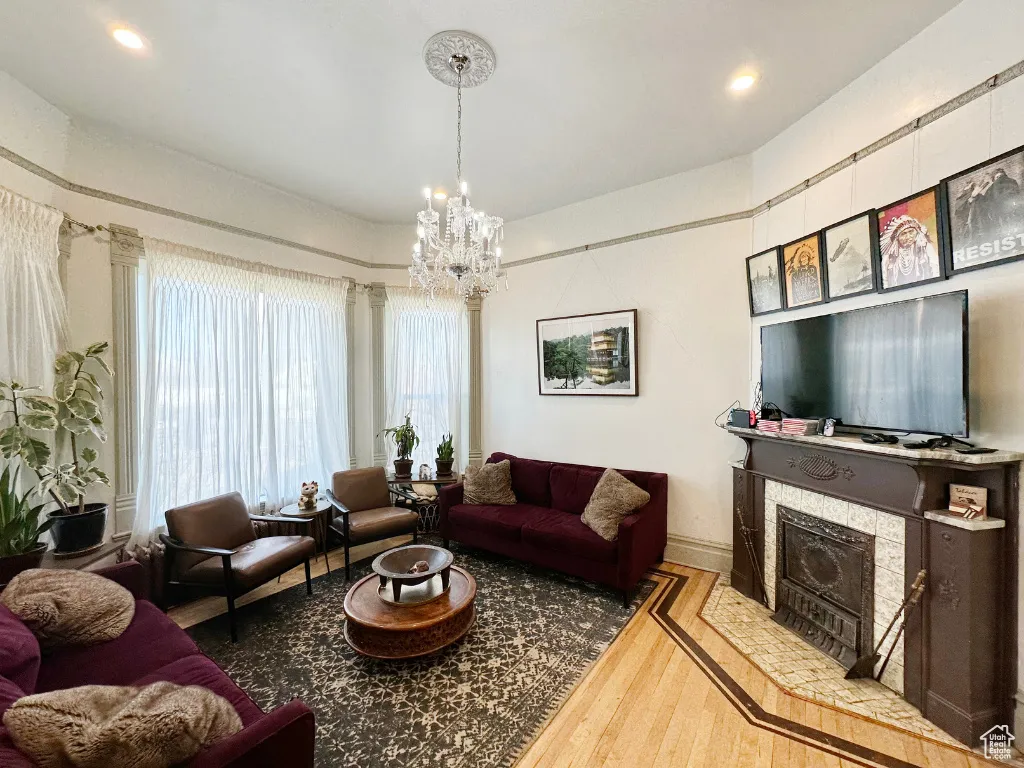 Living area with a tile fireplace, an inviting chandelier, and wood finished floors