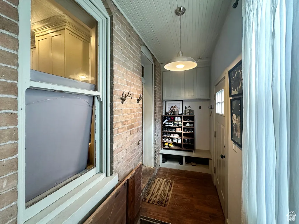Hallway featuring dark wood-style floors and brick wall