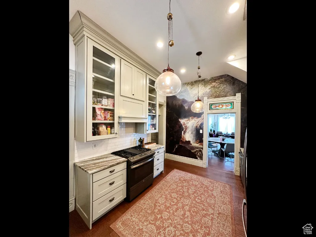 Kitchen featuring glass insert cabinets, pendant lighting, stainless steel range with gas cooktop, and light stone counters