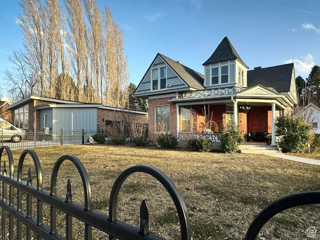 View of front facade with a porch, fence, brick siding, and a sink