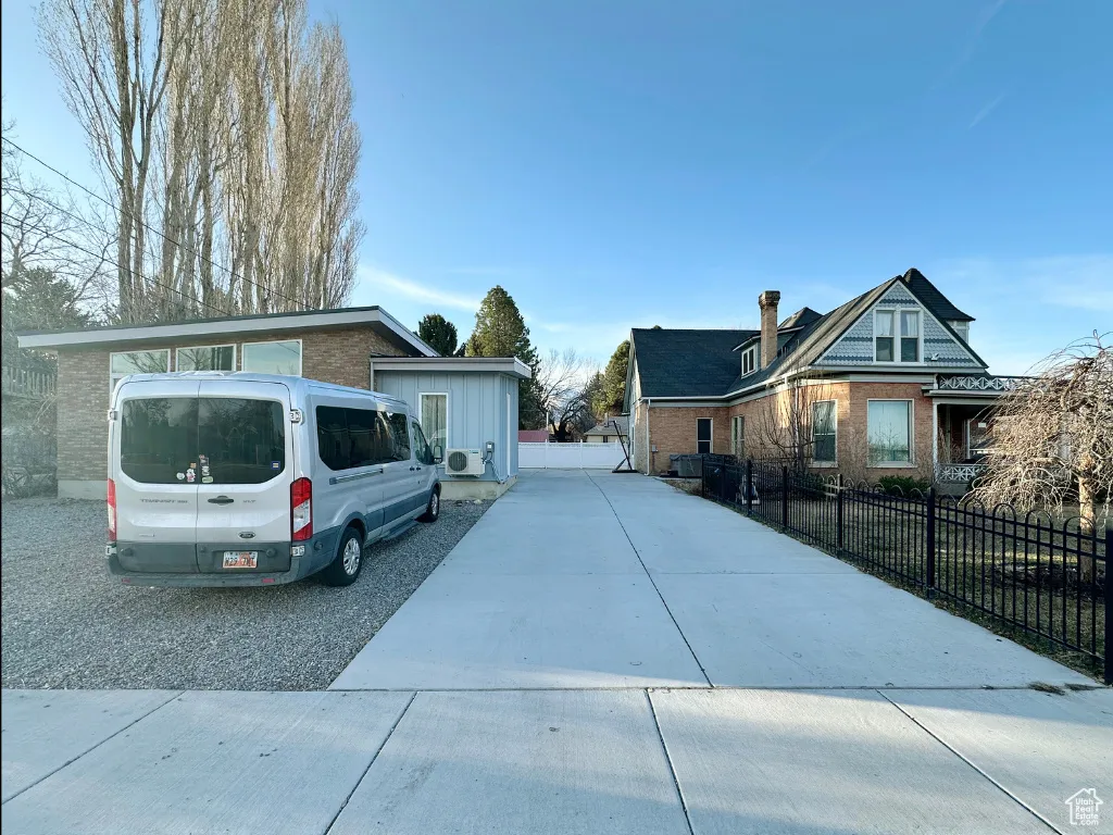 View of front of home featuring brick siding, driveway, and fence