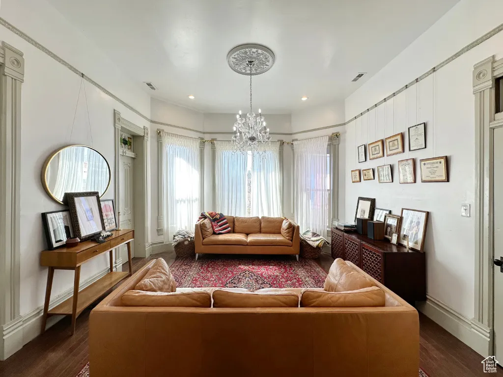Living area with visible vents, baseboards, a notable chandelier, and dark wood finished floors