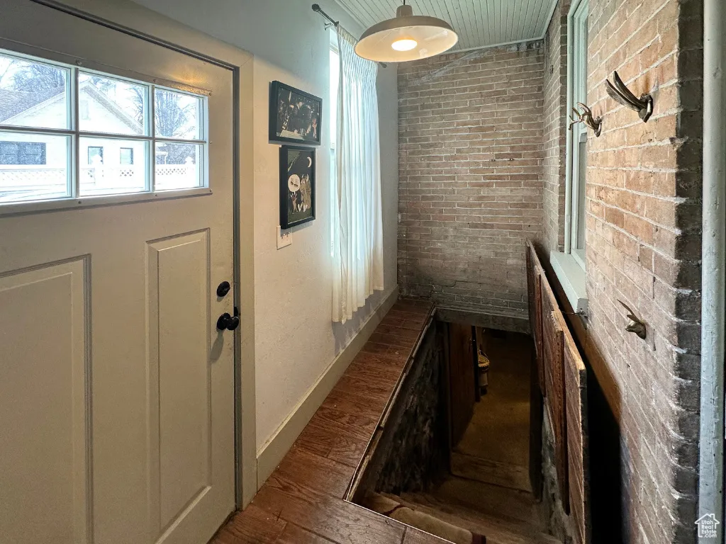 Interior space with brick wall, baseboards, and wood finished floors