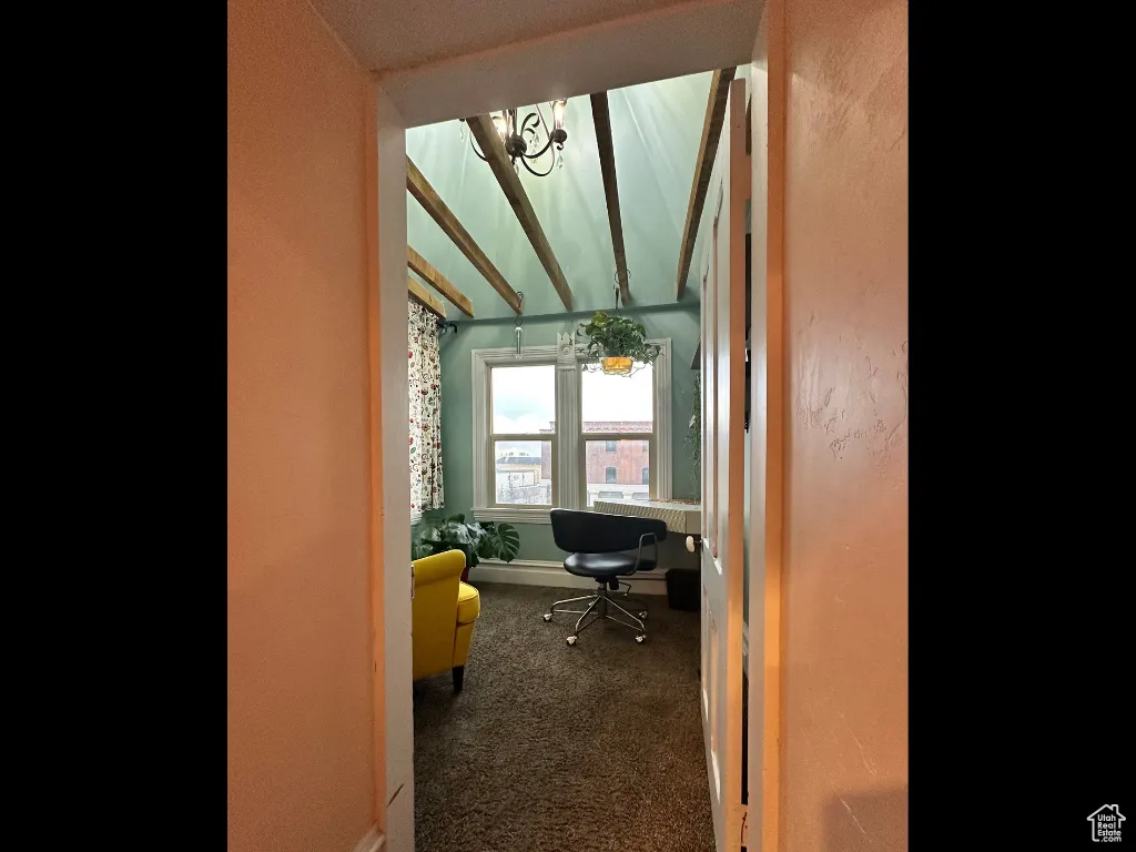Carpeted office space with baseboards, a notable chandelier, and vaulted ceiling