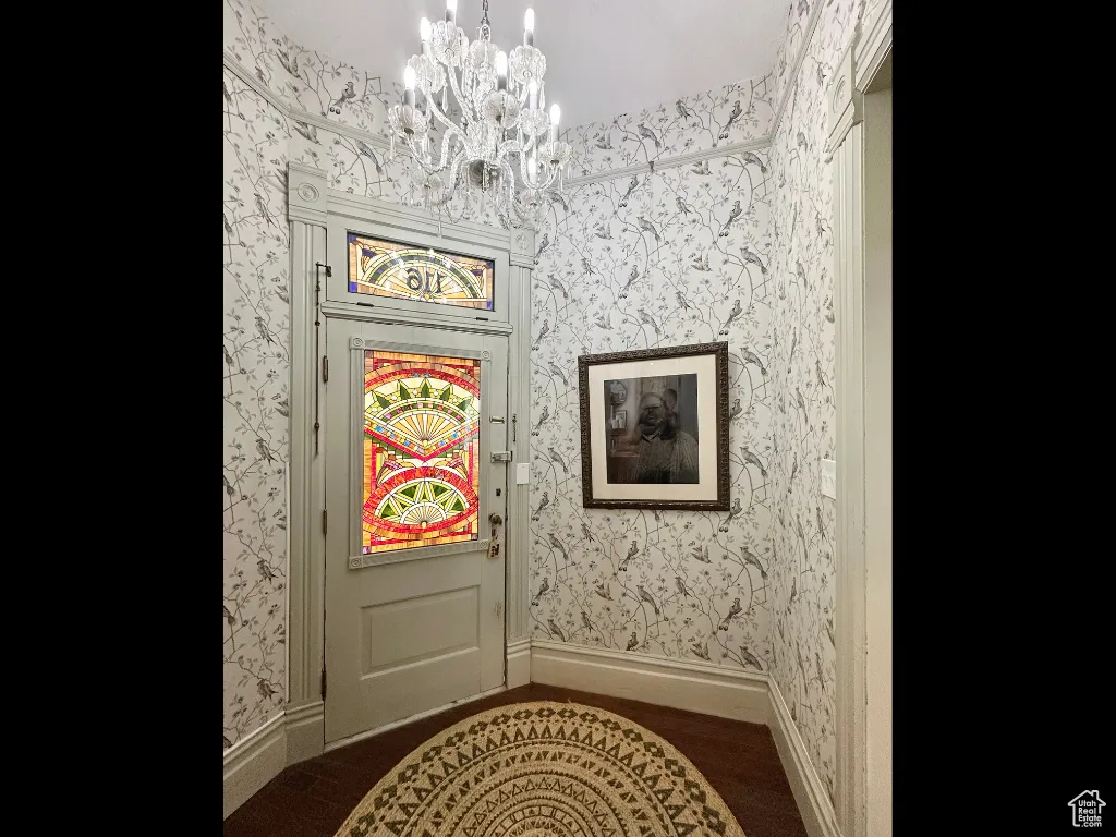 Entryway with wallpapered walls, baseboards, and a chandelier
