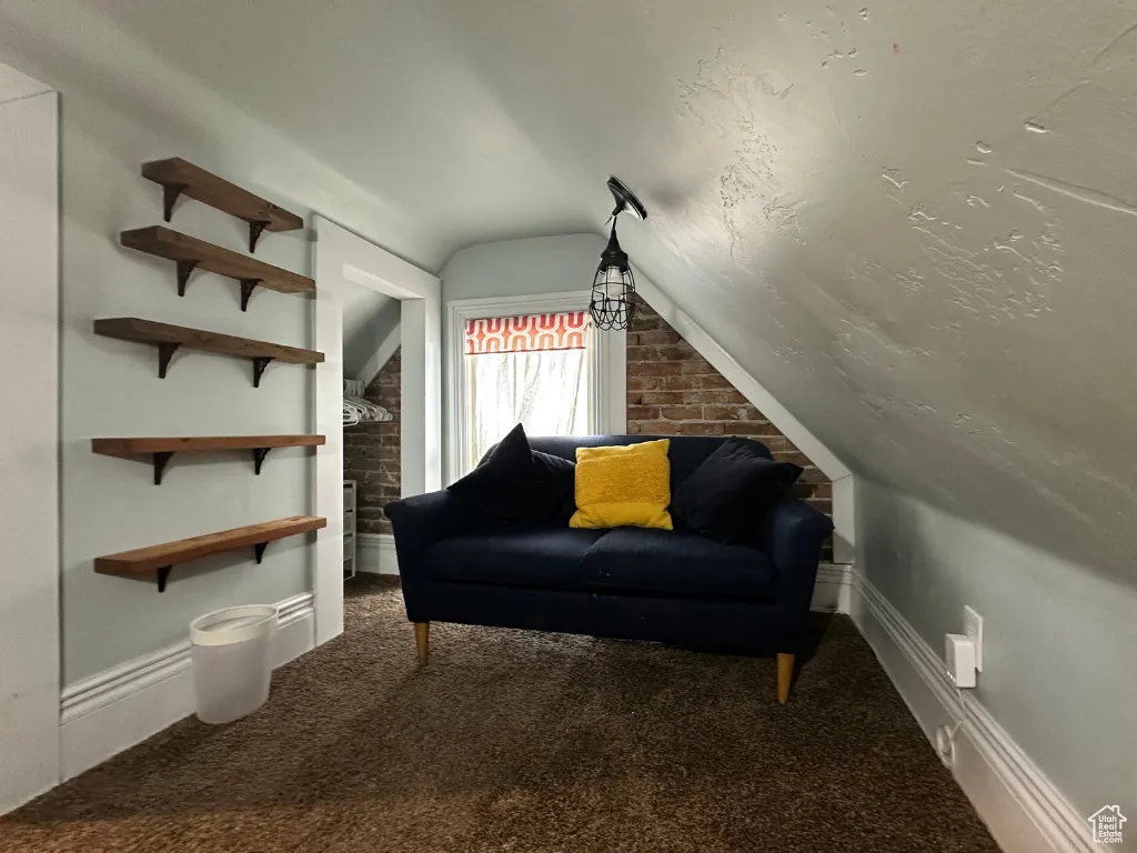 Sitting room featuring brick wall, lofted ceiling, and carpet