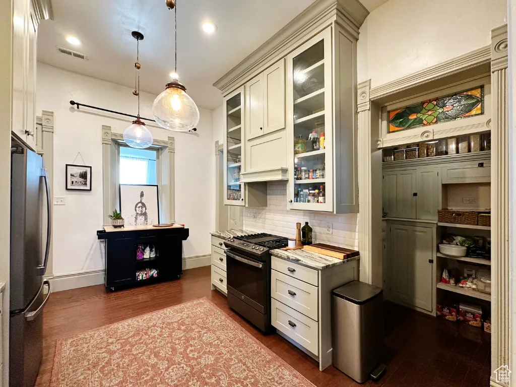 Kitchen with dark wood-style floors, visible vents, stainless steel appliances, decorative backsplash, and glass insert cabinets