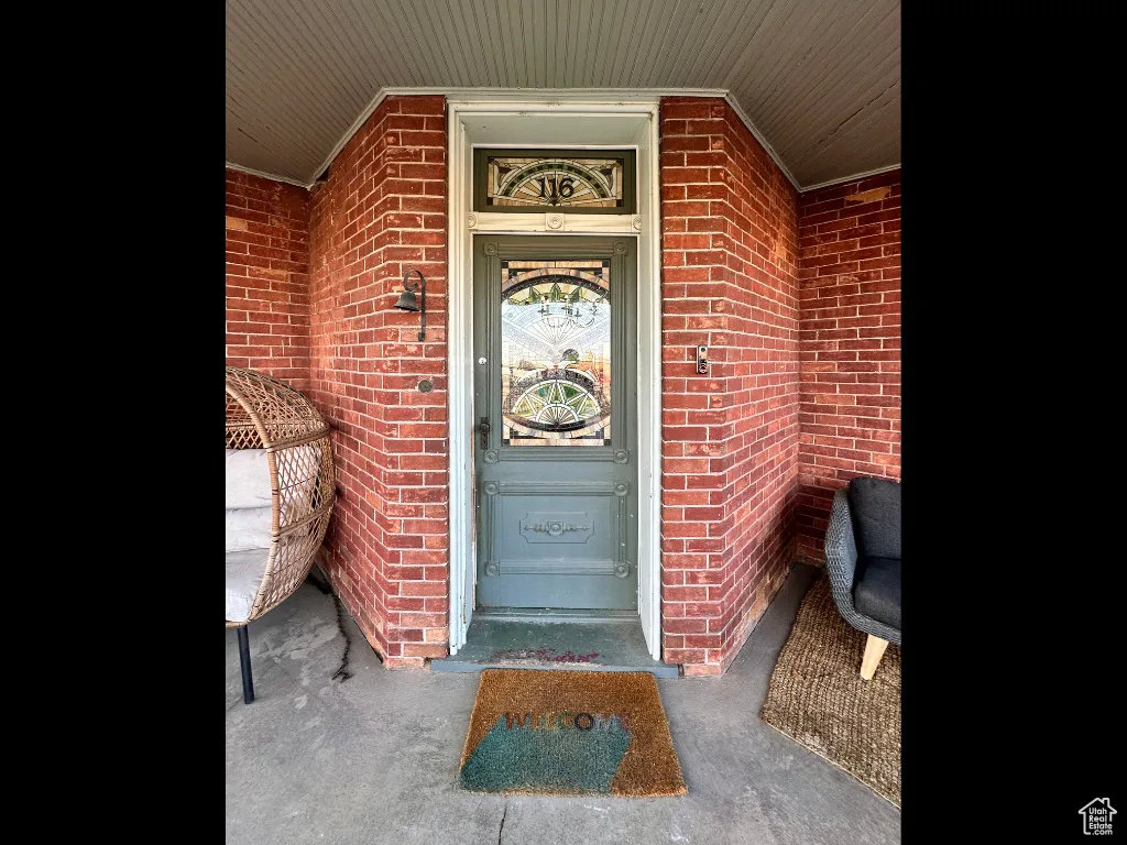 View of exterior entry with a porch and brick siding